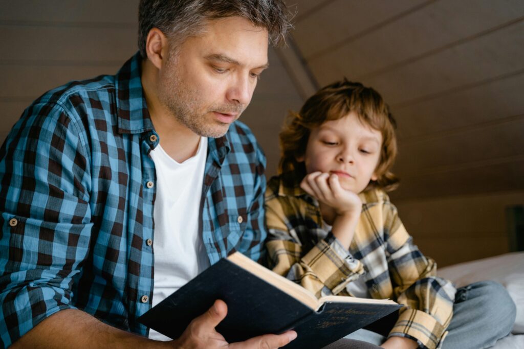 Padre leyendo un cuento a su hijo, la imagen ilustra como en familia se puede acompañar a un niño a manejar la ansiedad por separación

